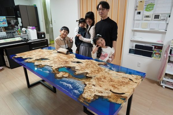 蓄光の波を演出したレジンテーブルを前に笑顔で立つ家族